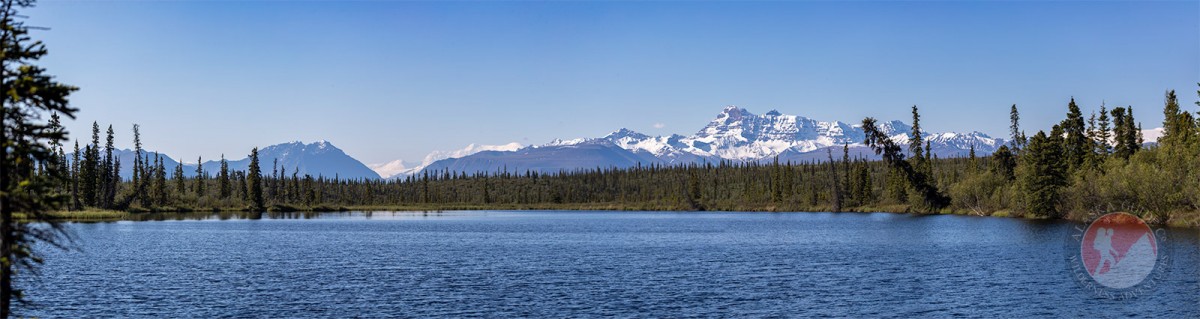 Looking across Rock Lake from left to right seeing Parka Peak, Atna Peaks, and Rime Peak covered in snow and Tanada Peak in the mid-ground.