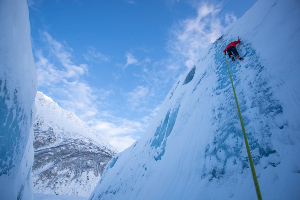 A climber nears the top of an iceberg.