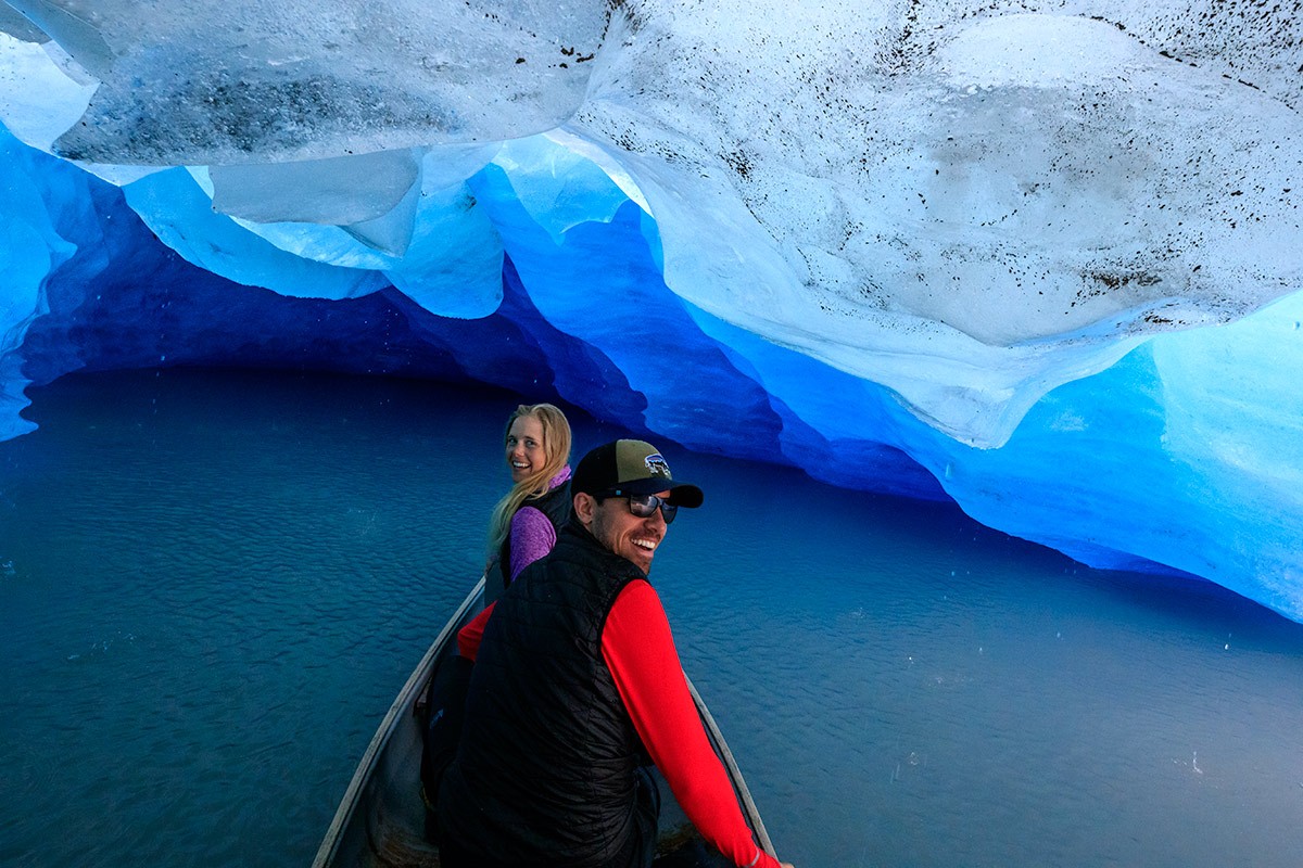 A couple canoe into an ice cave on the iceberg canoeing portion of the tour.