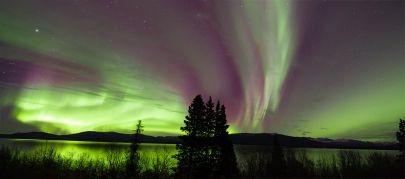 The auroras dance across the sky and Dezadeash Lake while touring above Haines.