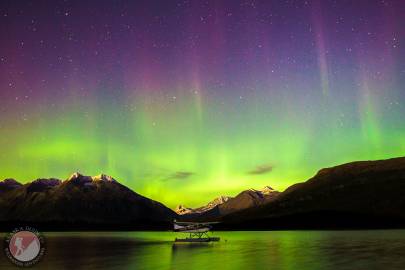 The northern lights dance above the Chugach Mountains and reflect on Robe Lake. Valdez, Alaska.